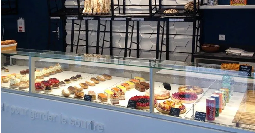 Vitrine réfrigérée avec gâteaux colorés exposés.