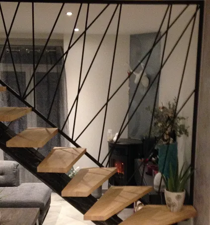 Escalier suspendu avec marches en bois et garde-corps en métal.